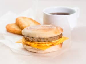 english muffin breakfast sandwich with coffee and hashbrowns