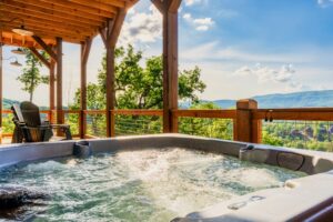 The six person hot tub with a view and string lights, located on the lower deck.